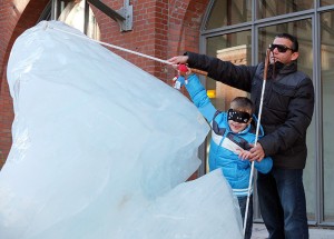 Das Bild zeigt Juan Ruiz und ein Kind beim Entdecken einer Eisskulptur. Sie erfassen ihre Form.